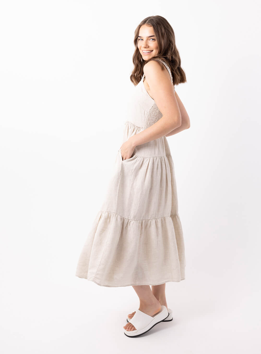 The Finlay Linen dress in beige is made from 100% breathable linen, featuring a tiered skirt, thin rouched straps and 2 side pockets