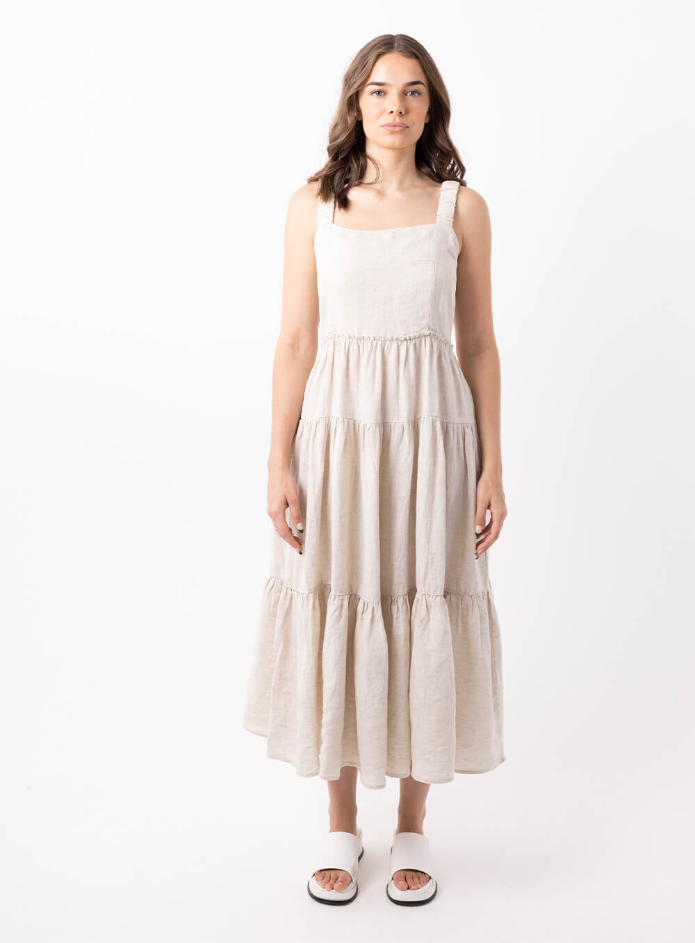 The Finlay Linen dress in beige is made from 100% breathable linen, featuring a tiered skirt, thin rouched straps and 2 side pockets
