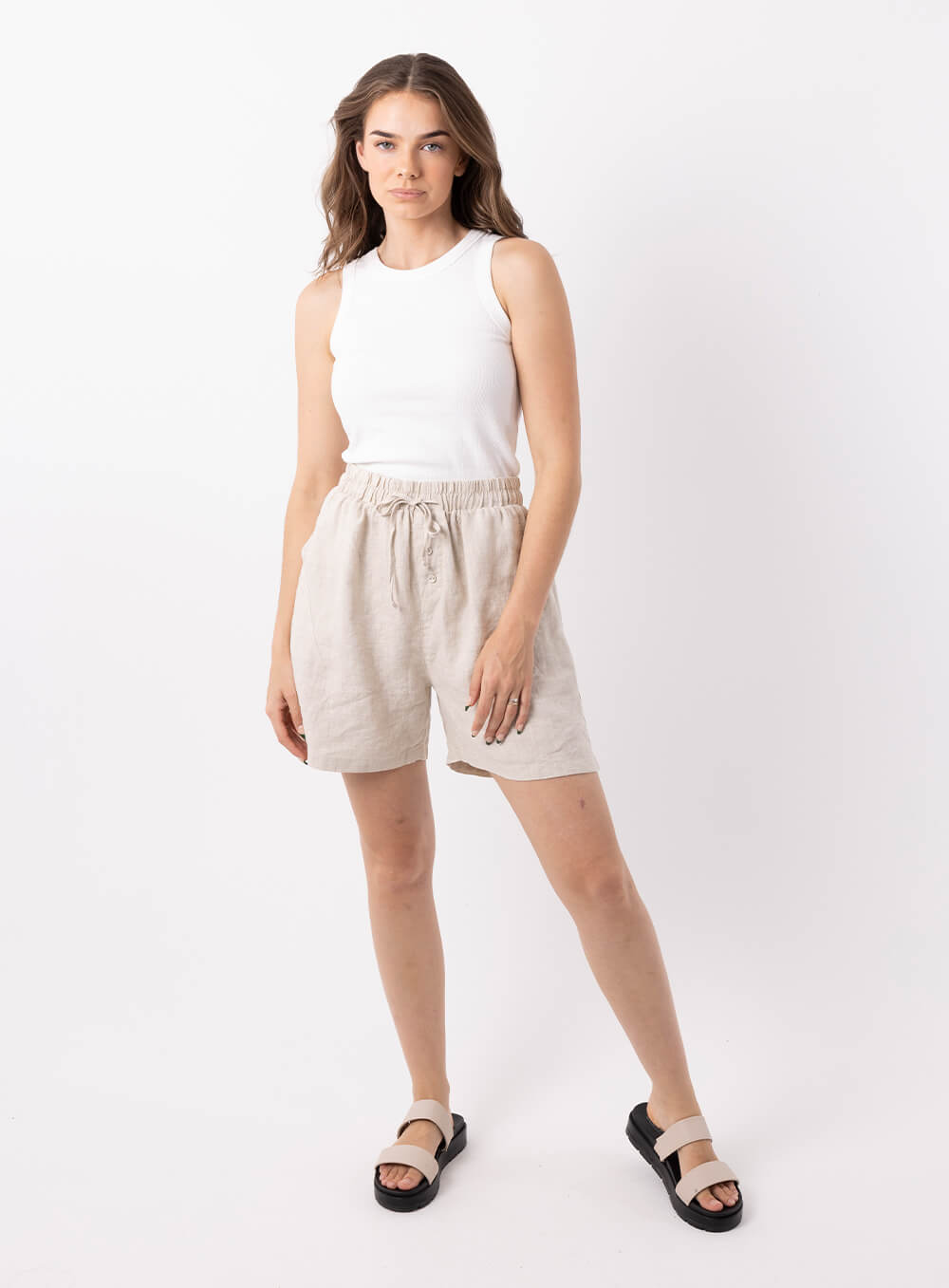 Adeline linen short in beige has 20mm elestic wiast band with tie. It has 2 side pockets, is mid thigh length with 100% breathabe linen fabric.. 