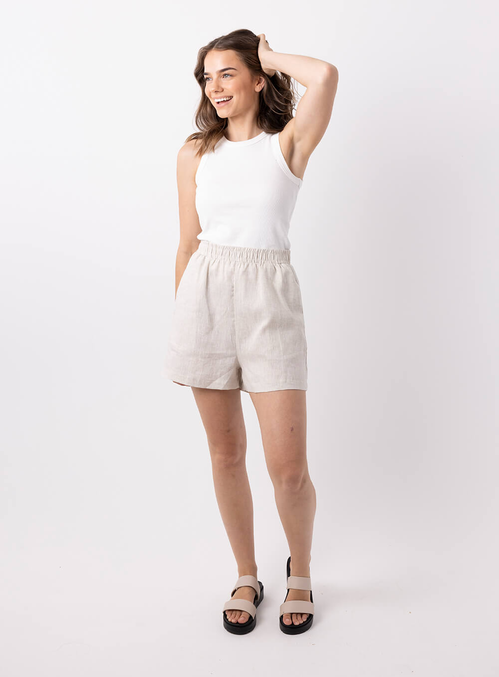 The Ali Linen Short in biege is 100% breathable lien, mid thigh in length with 2 side pockets, no back pockets, elastic waistband and designed to be worn high wiasted and loose fitting