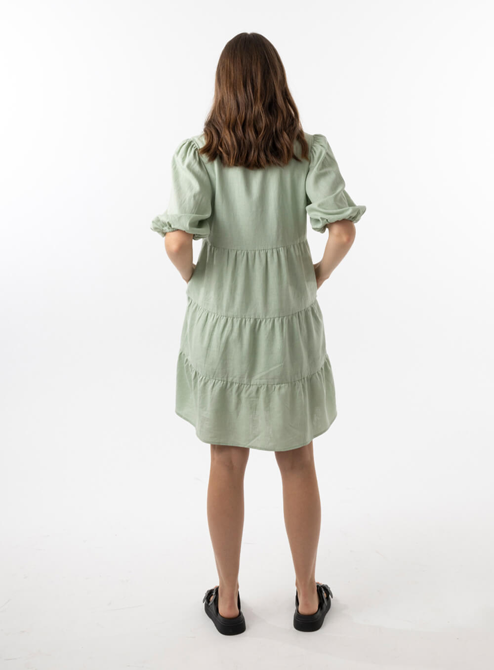 The Eleanor mini dress in sage features a flowing layered a line shape with draping linen/viscose fabric, puff 3/4 sleeves with elastic cuff which can be pushed up to the elbow, a dropped v shape neckline with a square finish.