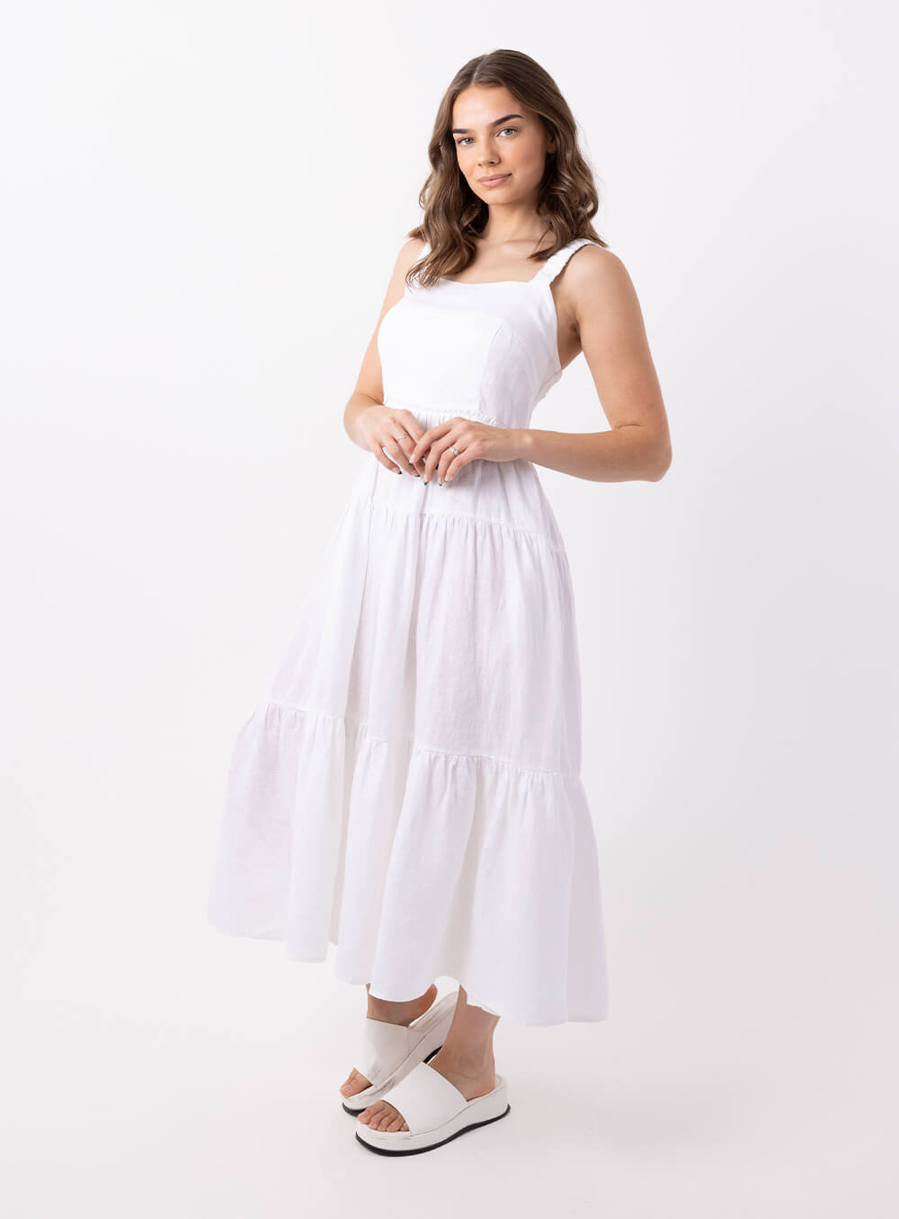 The Finlay Linen dress in white is made from 100% breathable linen, featuring a tiered skirt, thin rouched straps and 2 side pockets