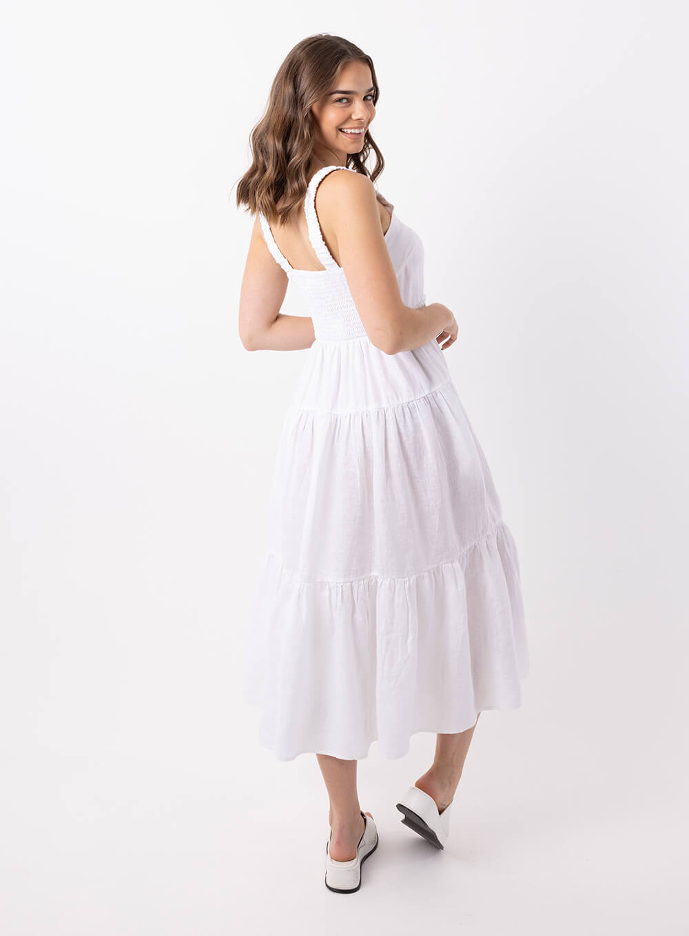 The Finlay Linen dress in white is made from 100% breathable linen, featuring a tiered skirt, thin rouched straps and 2 side pockets