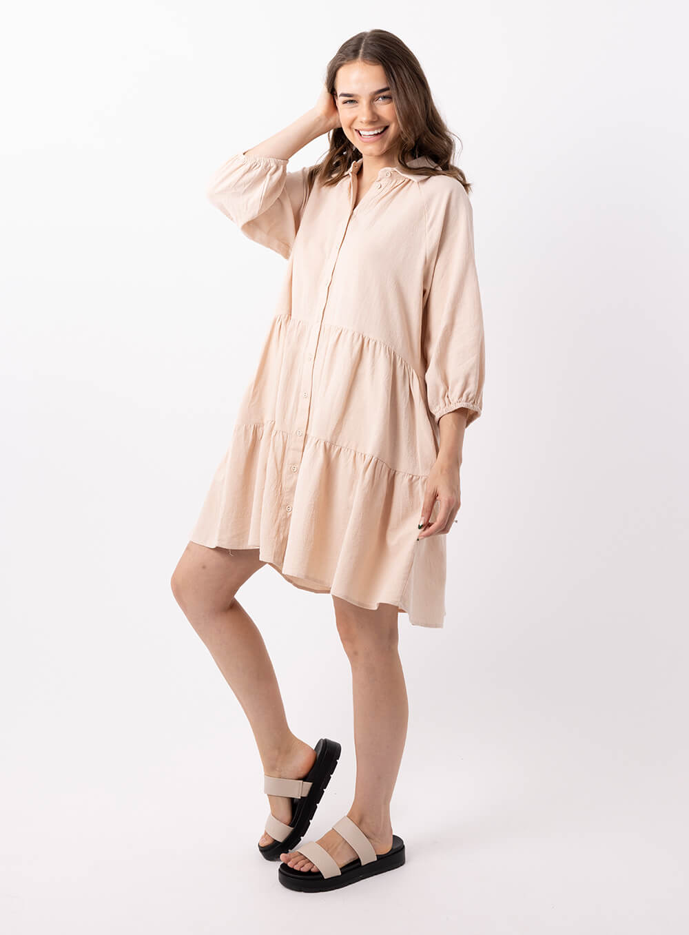 The Jasmine Dress in beige is made of 100% soft cotton, featuring a collar neck, 3/4 sleeve with elastic cuff button through front all the way to the hem, tiered layers through the body, midi in length and 2 side pockets
