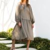 female model wearing Ada Line Dress-khaki midi dress with knee high boots on clear backdrop with floorboards