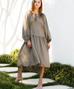 female model wearing Ada Line Dress-khaki midi dress with knee high boots on clear backdrop with floorboards