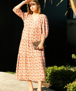 The Charlize linen dress has an all over brownie red print on a cream coloured background. It's lined, elasticated Sleeve, tiered style and front bodice detailing