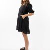The Eleanor mini dress in black features a flowing layered a line shape with draping linen/viscose fabric, puff 3/4 sleeves with elastic cuff which can be pushed up to the elbow, a dropped v shape neckline with a square finish.