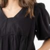 The Eleanor mini dress in black features a flowing layered a line shape with draping linen/viscose fabric, puff 3/4 sleeves with elastic cuff which can be pushed up to the elbow, a dropped v shape neckline with a square finish.