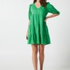 The Eleanor mini dress in green features a flowing layered a line shape with draping linen/viscose fabric, puff 3/4 sleeves with elastic cuff which can be pushed up to the elbow, a dropped v shape neckline with a square finish.