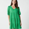 The Eleanor mini dress in green features a flowing layered a line shape with draping linen/viscose fabric, puff 3/4 sleeves with elastic cuff which can be pushed up to the elbow, a dropped v shape neckline with a square finish.
