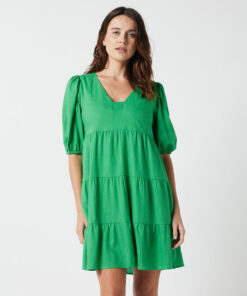 The Eleanor mini dress in green features a flowing layered a line shape with draping linen/viscose fabric, puff 3/4 sleeves with elastic cuff which can be pushed up to the elbow, a dropped v shape neckline with a square finish.